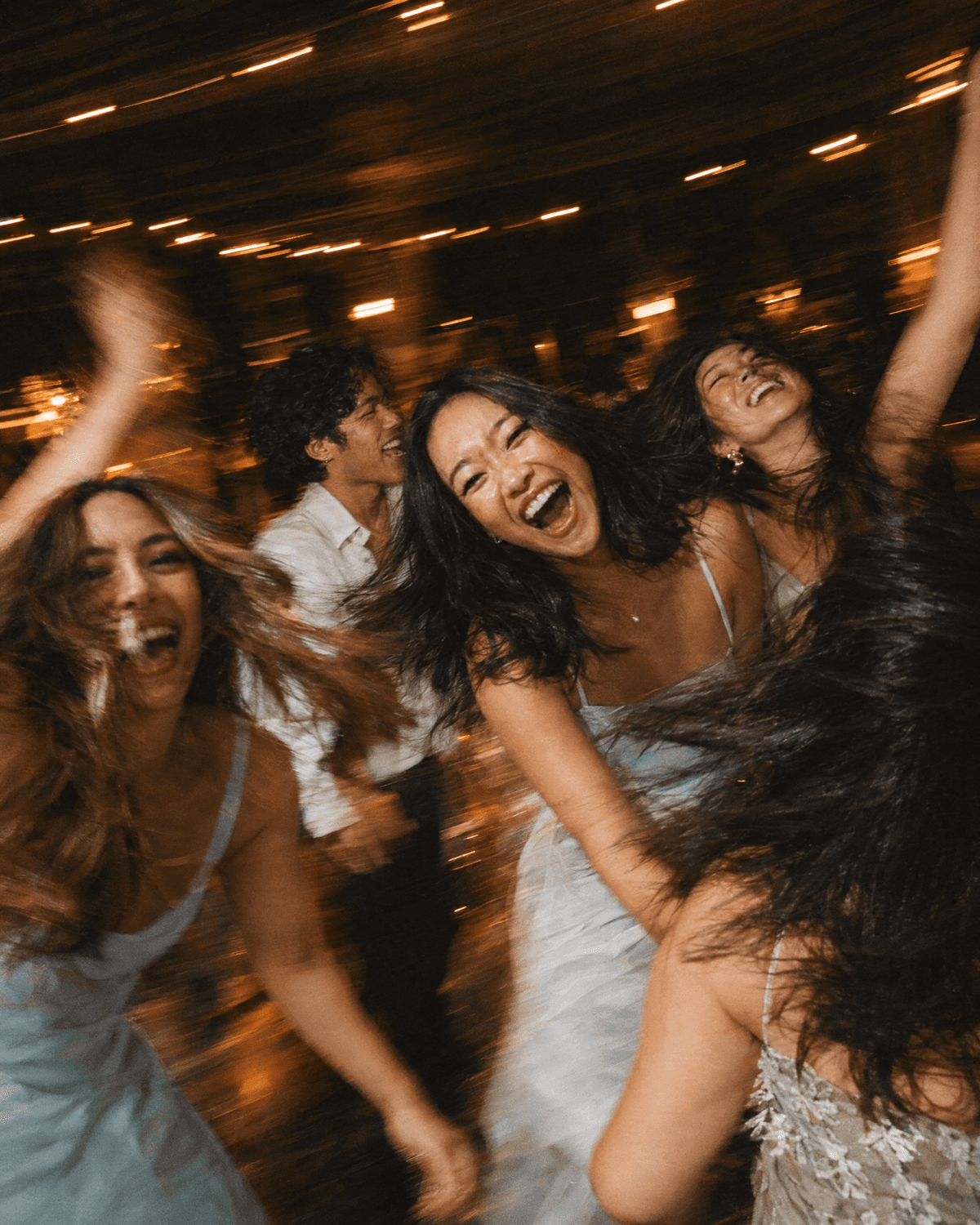 Friends spinning on the dance floor under string lights