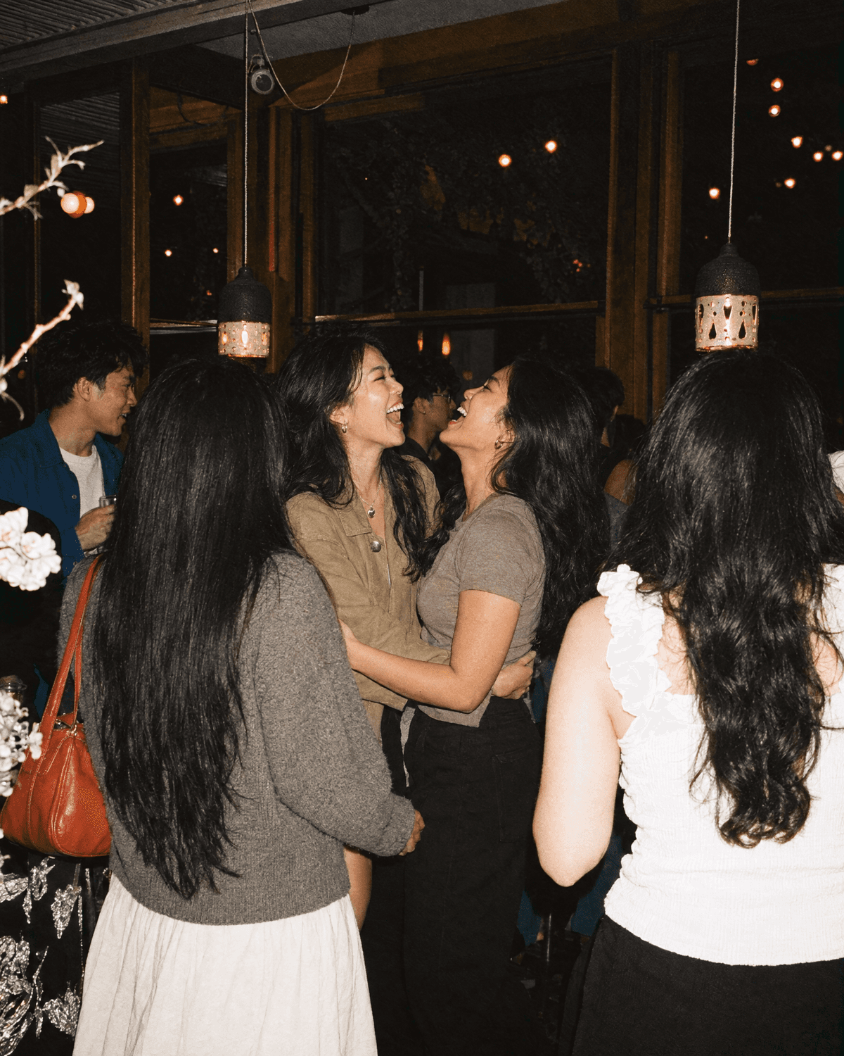 Two guests laughing face to face in a crowded reception room